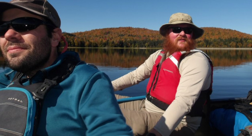 Two people sitting in a canoe smile at the camera. 